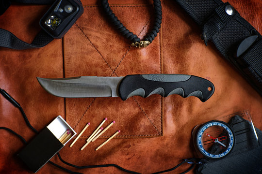 edc knife on leather background with compass