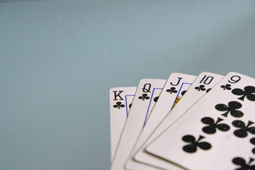 Club Straight Flush Playing Cards. Five card hands. Nine, Ten, jack, queen, king on blue grey background. Poker hand and card games. Club suit almost a royal flush, gambling. Las Vegas