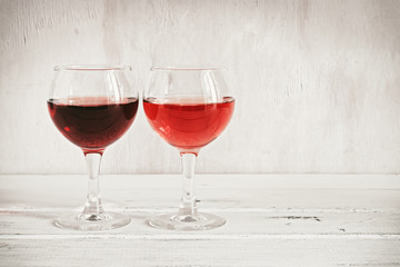 Two glasses with red and pink wine on a white wooden table. Side view, copy space.