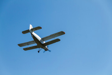 a retro biplane flying at high speed high in the air against a blue, cloudless sky.