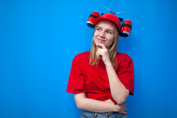 thoughtful happy girl a fan in a red uniform and a beer hat looks at a place for text, a cheerleader dreams on a blue background