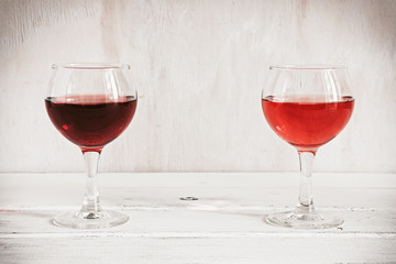 Red and rose wine in glasses on a white rustic wooden table. Place for text.