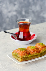 Fototapeta na wymiar BAKLAVA. Traditional Turkish Desserts Baklava with Turkish Tea. Crispy pistachio baklava on white plate.