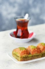 BAKLAVA. Traditional Turkish Desserts Baklava with Turkish Tea. Crispy pistachio baklava on white plate. .