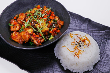 crispy fried chinese style chili chicken with jasmine rice in a black plate