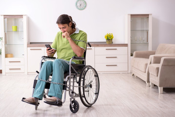 Young male invalid in wheel-chair suffering at home