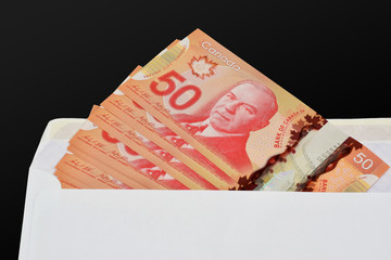 An illustrative concept image of $50 (Fifty) Canadian dollar (CAD) banknotes in a white envelope to...