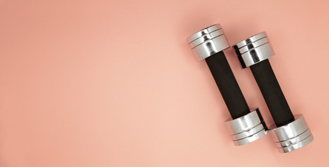 Metal small dumbbells on a pink background.
