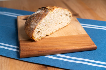 Homemade boule (round loaf) of freshly baked sourdough bread on a wood cutting board