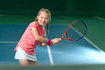 A girl plays tennis on an indoor tennis court.