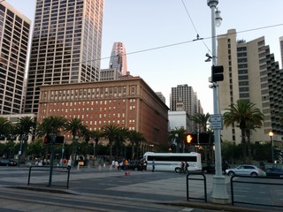 The Embarcadero, Downtown San Francisco, California, USA - High rises and historic and modern architecture along The Embarcadero, with palm trees in the background at the street intersection.