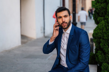 Young business man with white shirt and tie in outdoor city making a phone call