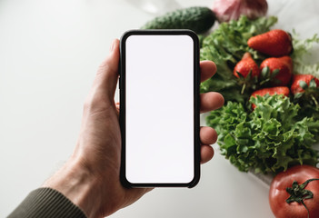 Hand hold the smartphone with white screen, mock up. Online food market concept.