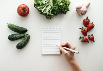 Woman makes notes in a notebook, food shopping list or writing recipes. Mock up. Flat lay