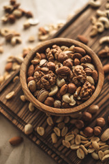 Different types of nuts, nut mix of almonds, hazelnuts, cashews, peanuts on a wooden bowl. Close up