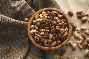 Different types of nuts, nut mix of almonds, hazelnuts, cashews, peanuts on a wooden bowl. Close up