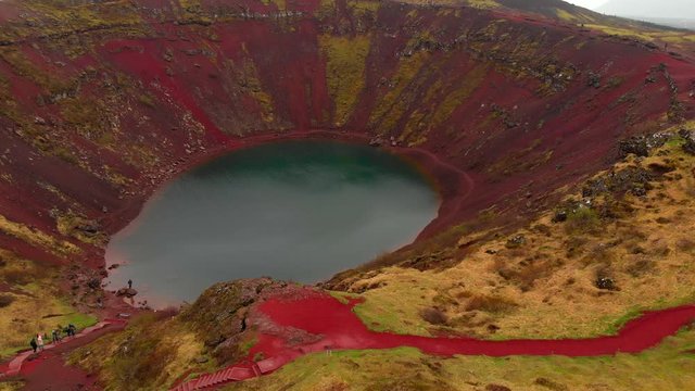 Aerial 4k view of an Icelandic crater lake on top of Kerio Volcano with tourists walking on top of it,