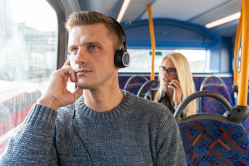 People travelling by bus in London and keeping social distance - Man and woman commuting on empty...