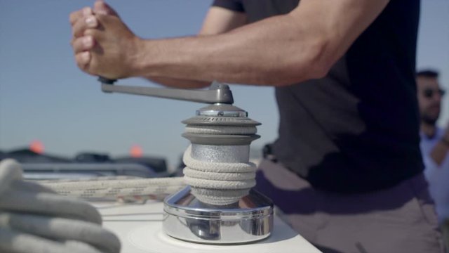 A sailor uses a rope and pulley to raise/lower a sail in a Sunny Day, HD