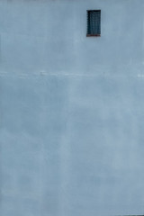 Ventana con cortina blanca sobre pared de edificio de color azul