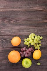 Obraz na płótnie Canvas fruits on a wooden table. located on the bottom. apple, orange, grapefruit, lemon, grape. place for text. wooden background. view from above