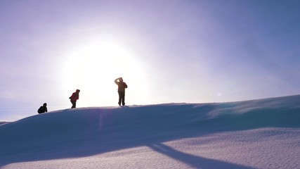 Travelers walk along top of a snowy ridge in the rays of the beautiful sun. a team of tourists strives for victory and success. business teamwork. beautiful nature of alaska, north.