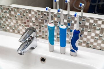 Three electric toothbrushes stand on the washbasin.