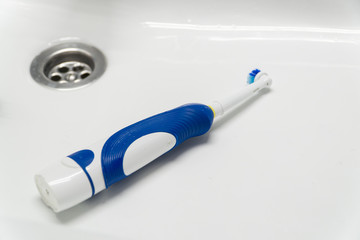 Electric toothbrush on white background. An electric toothbrush lies in the wash basin.