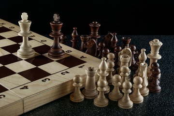 two chess kings on a chessboard and other chess pieces out of game on black background. watching...