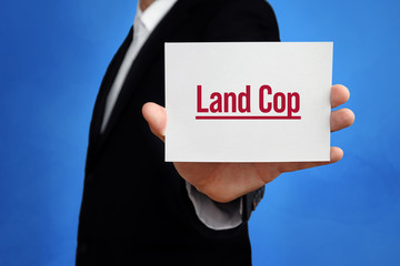 Land Cop. Lawyer holding a card in his hand. Text on the board presents term. Blue background. Law, justice, judgement