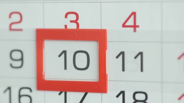 Woman's hand in office changes date at wall calendar. Changes 9 to 10