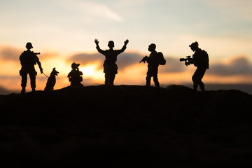 Fototapeta na wymiar Battle scene. Military silhouettes fighting scene on war fog sky background. A German soldiers raised arms to surrender.