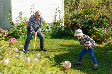 Grandfather plays with his grandson in nature in summertime. Elderly father plays sports with his...