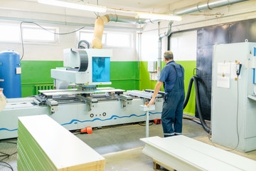 Male working on cnc machines in the furniture factory. Wooden furniture production. Joinery.