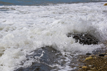 pebble stones on the sea beach, the rolling waves of the sea with foam