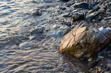 pebble stones on the sea beach, the rolling waves of the sea with foam