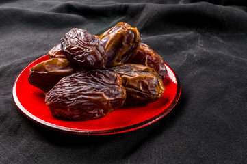 Big luxury dried date fruit in bowls on the dark surface, kurma ramadan kareem concept, close up.