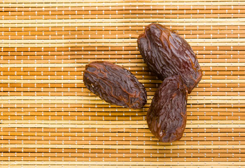Big luxury dried date fruit on the bamboo mat, kurma ramadan kareem concept, close up.