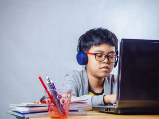 The boy wearing headphones sitting at the table with internet chat skype teacher prepare for exam...