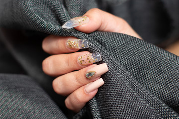 Manicure golden nails with diamonds on a grey background