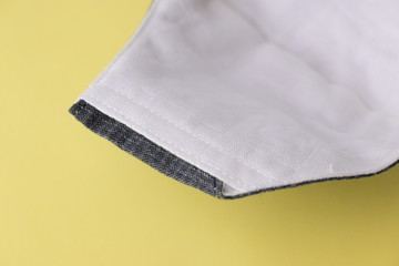 detail of cloth mask material with white salu muslin fabric soft textile, objects put on yellow background