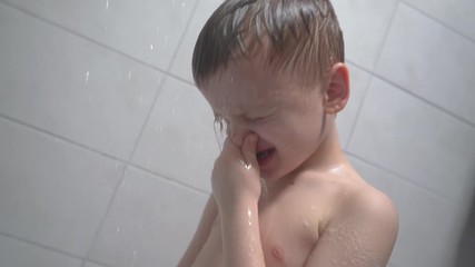 6-7 years old boy taking a bath, washes in the shower and smiles joyfully