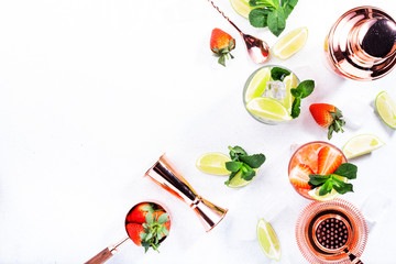 Fresh Mojito cocktail set with lime, mint, strawberry and ice in glass on gray background. Summer cold alcoholic non-alcoholic drinks, beverages and cocktails. Steel bar tools. Copy space