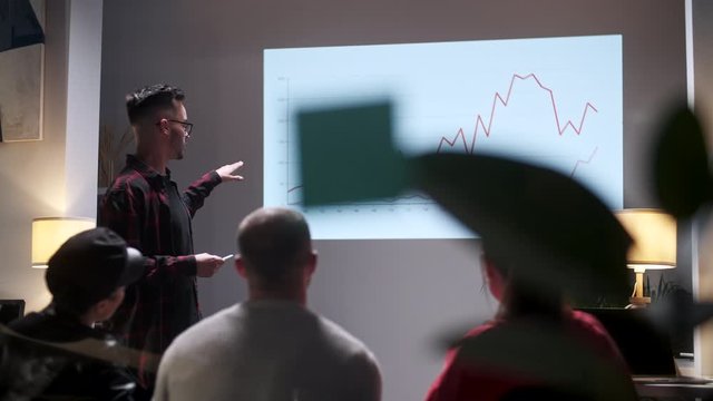 Business meeting. Office Team Analyzes Business Growth. Young Man Interested In Audience. On Screen Growth Graph Monitor