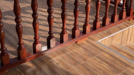 High angle and diagonal view of vintage glossy wood banister on wooden tile floor with stairway