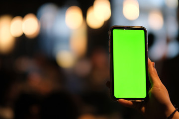 close up one hand showing green screen smart phone. blurred bokeh background