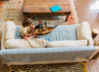 overhead view of 6 year old boy playing with his pirate ship on  sofa