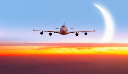 Fototapeta premium Airplane in the sky with crescent moon at sunset 