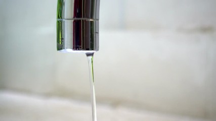 Crystal clear drops of water falling slowly from old brown pipe outdoors. Rusty tap needs reparing. Close-up stream of water splashing on blurred background. Pure water for people hygiene. Loop Video - Powered by Adobe