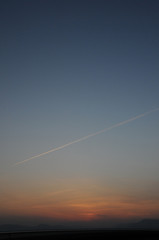 地平線に沈むきれいな夕日と飛行機雲